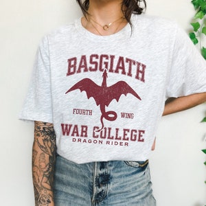 May include: A grey t-shirt with a red dragon graphic and the text "Basgiath Fourth Wing War College Dragon Rider".