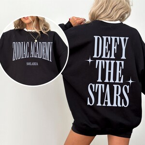 May include: Black sweatshirt with the text "Zodiac Academy Solaria" on the front and "Defy the Stars" with two small stars on the back.