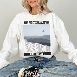 Puede incluir: Sudadera blanca con un estampado gr&aacute;fico de una cordillera y el texto "The Riders Quadrant Basgiath War College".