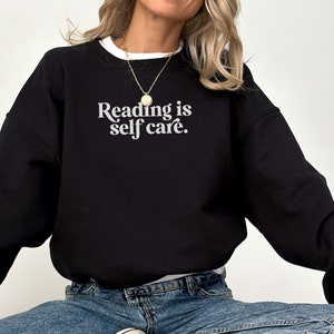 May include: Black sweatshirt with the text "Reading is self care." in white lettering.