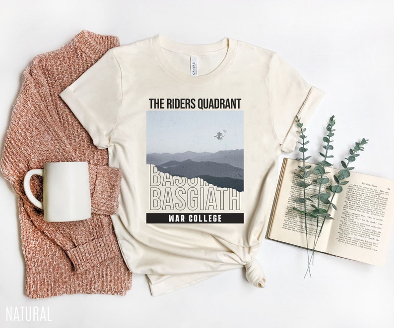 K&ouml;nnte beinhalten: Ein naturfarbenes T-Shirt mit einem grafischen Design, das eine Bergkette und den Text "The Riders Quadrant, Basgiath, War College" zeigt.