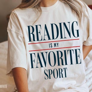 May include: White t-shirt with the text "Reading is my favorite sport" in black and red.