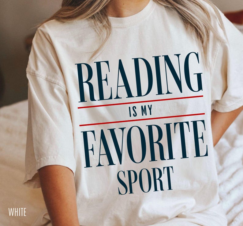 May include: White t-shirt with the text "Reading is my favorite sport" in black and red.