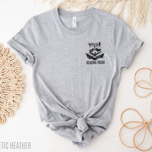 May include: Grey t-shirt with a raccoon reading a book and the text "Reading Trash" on the front.
