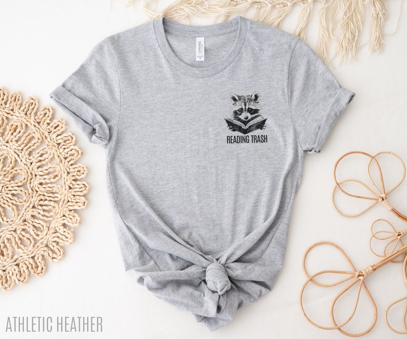May include: Grey t-shirt with a raccoon reading a book and the text "Reading Trash" on the front.