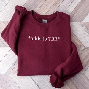 May include: Maroon sweatshirt with the text "*adds to TBR*" in white.