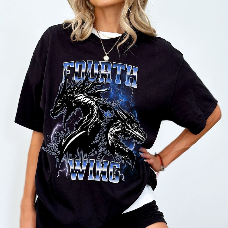 K&ouml;nnte beinhalten: Schwarzes T-Shirt mit einem grafischen Druck von zwei Drachen und dem Text "FOURTH WING" in Blau und Wei&szlig;.