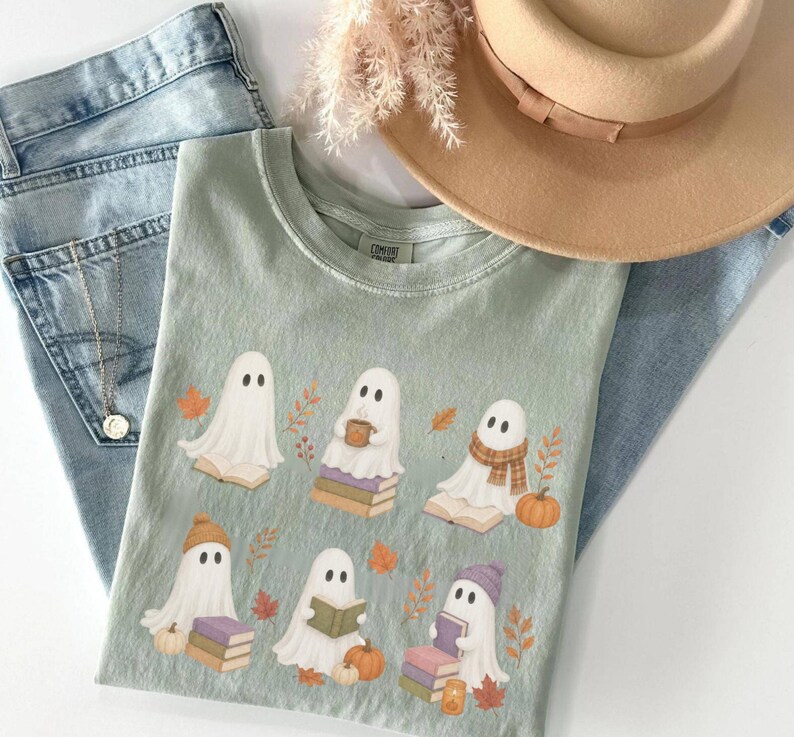 Bay Comfort Colors shirt featuring six cute Halloween ghosts reading and sitting on books, surrounded by pumpkins, autumn leaves, and cozy fall accessories.