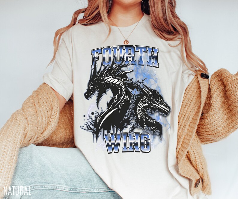 K&ouml;nnte beinhalten: Ein wei&szlig;es T-Shirt mit einem Aufdruck von zwei schwarzen Drachen und dem Text "FOURTH WING" in blauer Schrift.