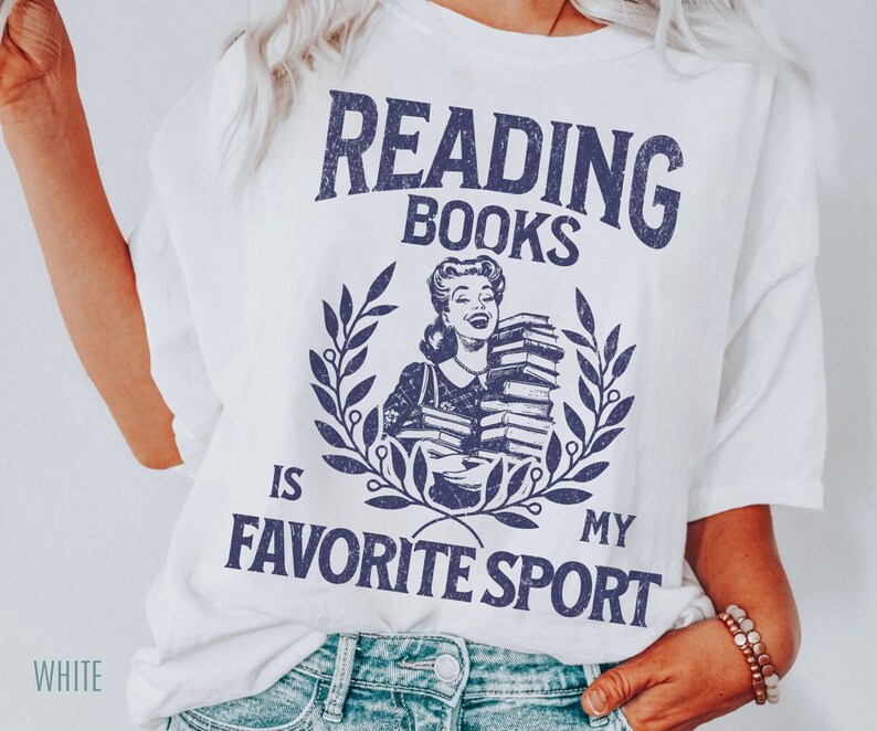 May include: White t-shirt with a navy blue graphic that reads "Reading Books Is My Favorite Sport." The design features a vintage illustration of a woman holding books, surrounded by a laurel wreath. The word "WHITE" is printed at the bottom left.