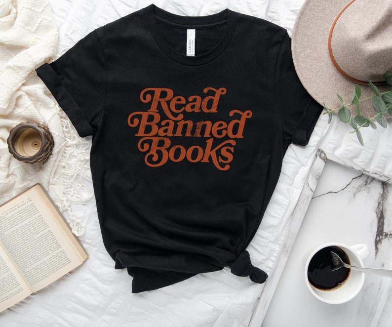 May include: Black t-shirt with the text "Read Banned Books" in orange retro font.