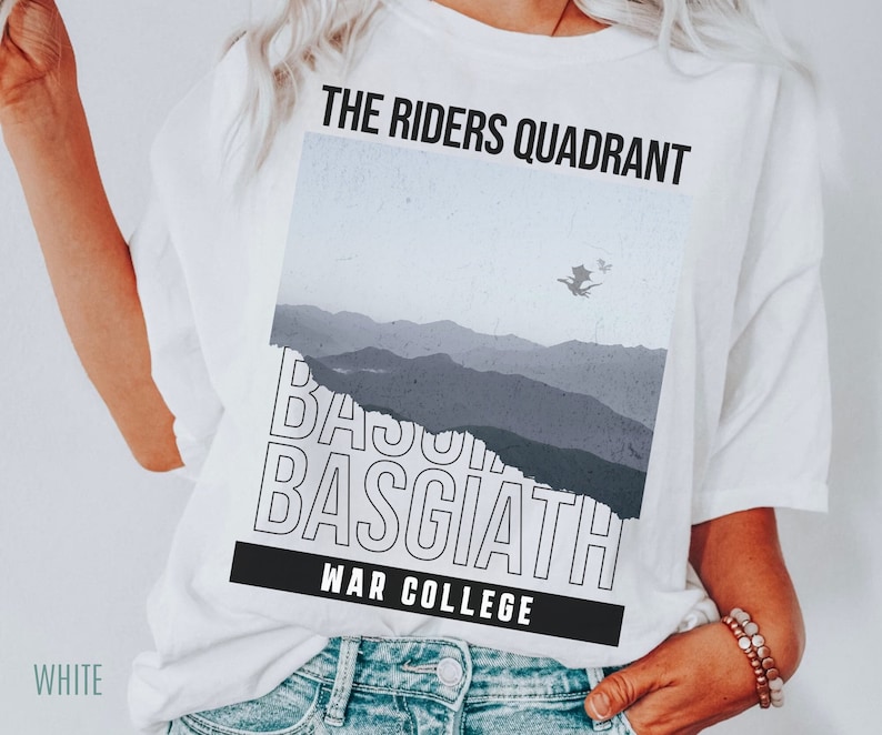 K&ouml;nnte beinhalten: Wei&szlig;es T-Shirt mit einem Grafikdesign, das eine Bergkette, einen Drachen, der am Himmel fliegt, und den Text "The Riders Quadrant", "Basgiath" und "War College" zeigt.