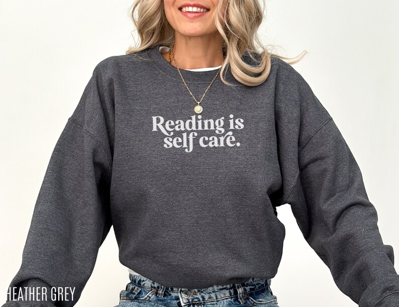 May include: Heather grey sweatshirt with the text "Reading is self care." in white.
