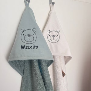 May include: Two hooded towels with a bear design and embroidered names. The towel on the left is green and says "Maxim". The towel on the right is white.