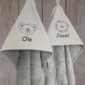 May include: Two gray hooded towels with embroidered animal faces and names. The towel on the left has a koala with the name "Ole" and the towel on the right has a lion with the name "Joost".