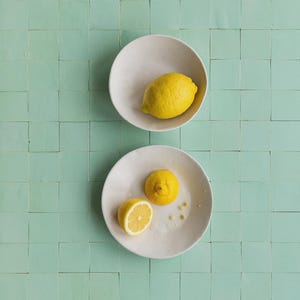 Può includere: Una tazza di ceramica bianca con manico nero e la scritta "But First, Coffee" in grassetto nero. La tazza è posta su uno sfondo sfocato, suggerendo un'atmosfera accogliente.
