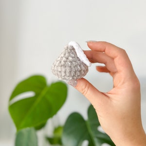 May include: A small gray and white crocheted ornament shaped like a teardrop. The ornament has a white crocheted loop at the top.