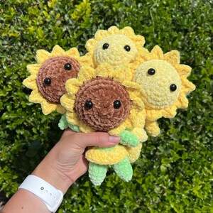 May include: Four crocheted sunflower plush toys. Two are brown and two are yellow. The sunflowers have black eyes and green stems.
