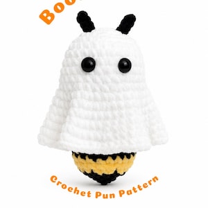 May include: A white crocheted ghost figure with black antennae and black eyes, featuring a yellow and black striped bee body underneath. The text BooBee Crochet Pun Pattern is printed in orange around the figure on a white background.