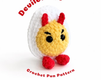 Puede incluir: Un juguete de peluche tejido a ganchillo con forma de huevo duro, con exterior blanco y centro amarillo. Presenta dos pequeños cuernos rojos en la parte superior, dos pies rojos en la base y ojos de plástico negro. El texto Deviled Egg Crochet Pun Pattern es visible.