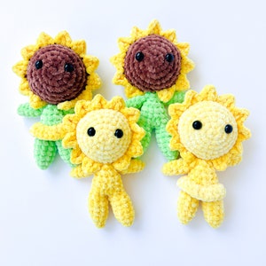 May include: Three crocheted sunflower plush toys. One sunflower is brown with green leaves, and the other two sunflowers are yellow with green leaves. All three sunflowers have black eyes.