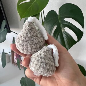 May include: Two gray crocheted kiss-shaped ornaments with white fuzzy tops.