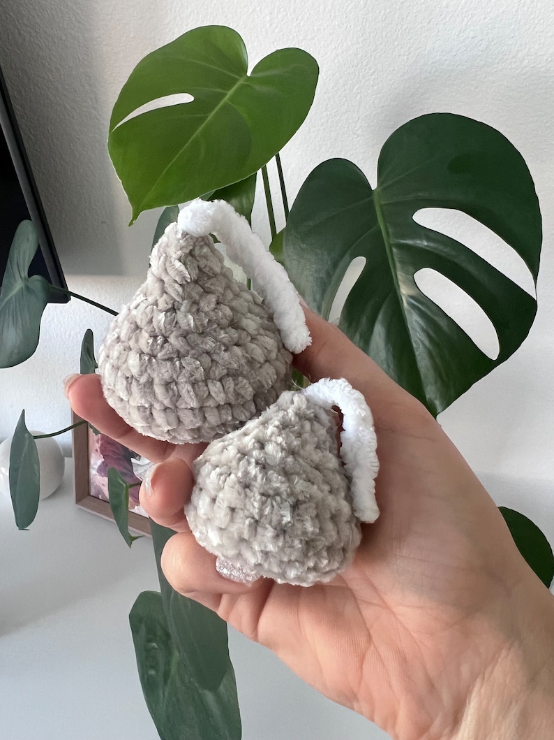 May include: Two gray crocheted kiss-shaped ornaments with white fuzzy tops.