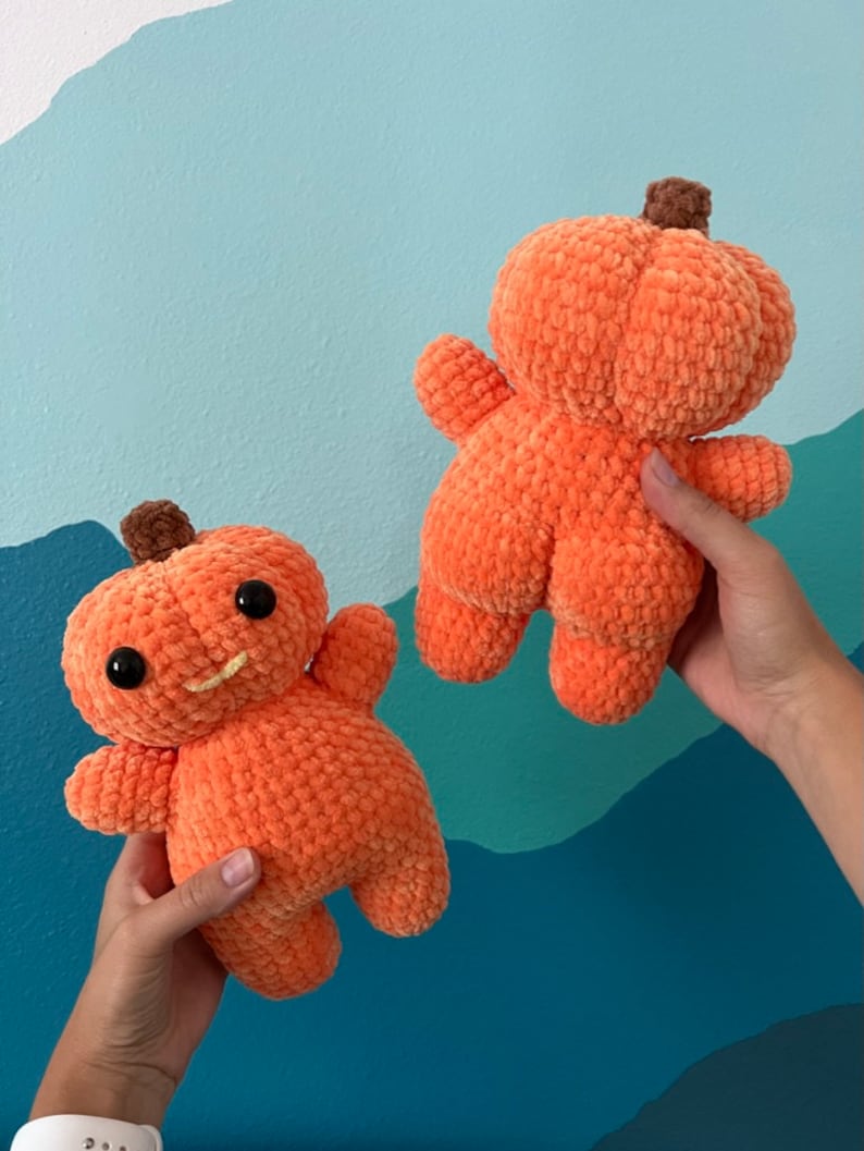 Peut inclure: Deux peluches en forme de citrouille orange crochet&eacute;es. Une citrouille a un visage souriant avec des yeux noirs et une bouche jaune. L'autre citrouille est unie.