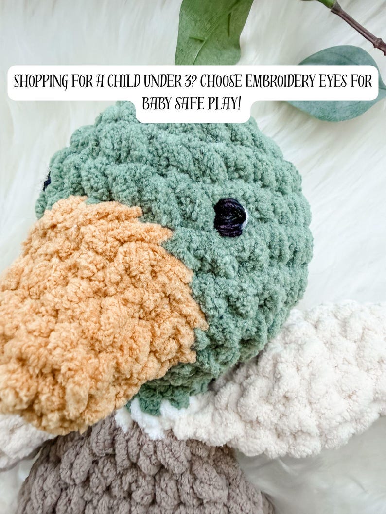 May include: A handmade plush duck toy with a green head, tan beak, and white and gray wings. The text "SHOPPING FOR A CHILD UNDER 3? CHOOSE EMBROIDERY EYES FOR BABY SAFE PLAY!" is displayed above the toy.