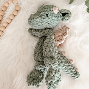 Peut inclure: Un dragon en crochet fait &agrave; la main, vert et beige. Le dragon a un aspect textur&eacute; et &eacute;pais, avec des ailes d&eacute;taill&eacute;es et de petits yeux ronds. Le jouet en peluche est con&ccedil;u pour &ecirc;tre doux et c&acirc;lin.
