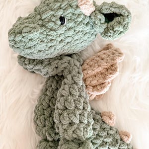 Peut inclure: Un dragon en crochet fait &agrave; la main, dans des tons de vert et de beige. Le jouet en peluche pr&eacute;sente un design d&eacute;taill&eacute; avec des &eacute;cailles textur&eacute;es, de petites cornes beiges et des ailes. Le dragon a une expression amicale avec un &oelig;il noir.
