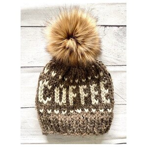 May include: A brown and white knit beanie with the word "COFFEE" knitted across the front. The hat has a large, fluffy, brown pom-pom on top. The hat is designed for cold weather.