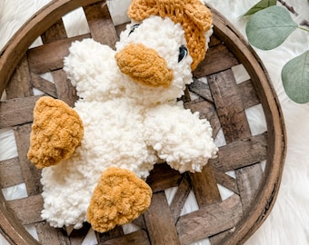 May include: A handmade crochet duck plush toy featuring a soft white textured body, a golden-brown beak, matching golden-brown feet, and a golden-brown textured headpiece. The duck has dark, round eyes and is crafted from plush yarn.