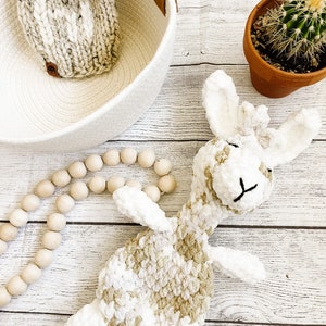 May include: A plush, cream and brown giraffe toy with a white background. The giraffe is lying on its side with its head resting on the floor.