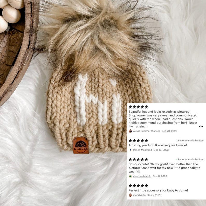 May include: A knitted baby hat with a fluffy pom pom on top. The hat is beige with white knit letters spelling "Hi".