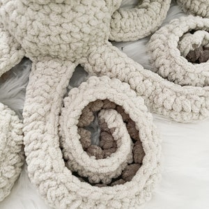 Pode incluir: Um brinquedo de polvo de croch&ecirc; em branco e marrom. O polvo tem oito tent&aacute;culos, que est&atilde;o enrolados em forma de espiral.