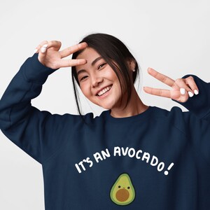 May include: A navy blue sweatshirt with a white graphic of an avocado with a smiling face and the text "It's an avocado!"