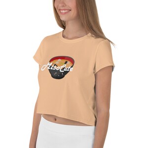 May include: A peach colored cropped t-shirt with short sleeves featuring a cartoon illustration of a bowl of miso soup with the text "MisoCute" in white.