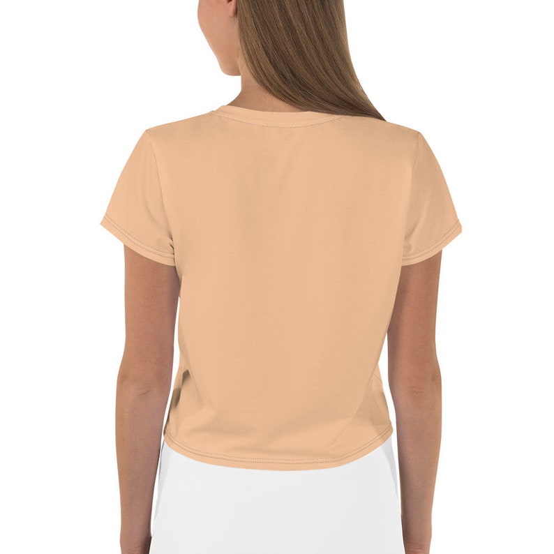 May include: A peach-colored cropped t-shirt with short sleeves. The shirt is made of a soft, comfortable fabric and has a relaxed fit.