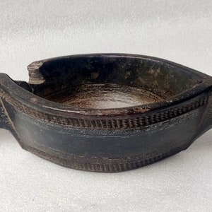 May include: A dark brown wooden bowl with a carved handle and intricate details. The bowl is shaped like a bird with a long beak.