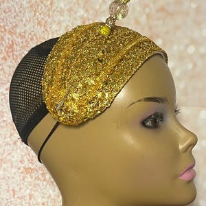May include: A gold sequined headband with a beaded embellishment. The headband is on a mannequin head.