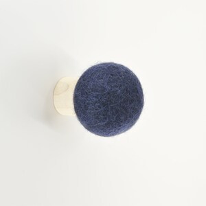 May include: A dark blue felt ball mounted on a wooden base. The ball is a decorative wall hook.