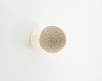 May include: A beige felt ball attached to a wooden base, a wall-mounted hook.