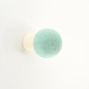 May include: A light green felt ball attached to a wooden base. This is a wall-mounted hook.
