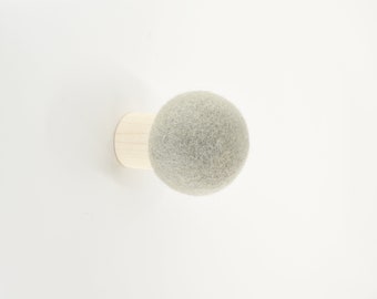 May include: A light gray felt ball attached to a wooden base. The ball is a decorative wall hook.
