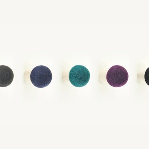 May include: Five wooden knobs with felt balls in different colors: dark gray, navy blue, teal, purple, and black.