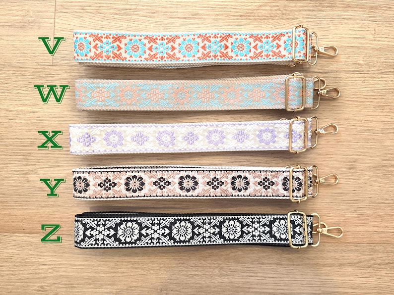 Pu&ograve; includere: Cinque tracolle regolabili etichettate da V a Z, ognuna con un motivo intrecciato unico. La tracolla V &egrave; arancione e blu, W beige e blu, X viola, Y nera e beige, e Z nera e bianca. Tutte includono componenti in metallo color oro.