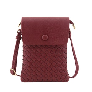 May include: A burgundy faux leather crossbody bag with a woven front panel and a flap closure with a gold button.