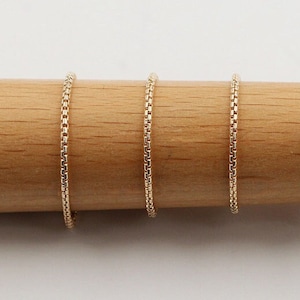 Puede incluir: Cinco collares de cadena de oro de diferentes longitudes, mostrados sobre una superficie de madera.