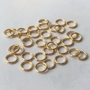 Könnte beinhalten: Ein Haufen goldener Sprungringe, eine Art von Schmuckzubehör, das zum Verbinden von Ketten, Schnüren und anderen Schmuckkomponenten verwendet wird.